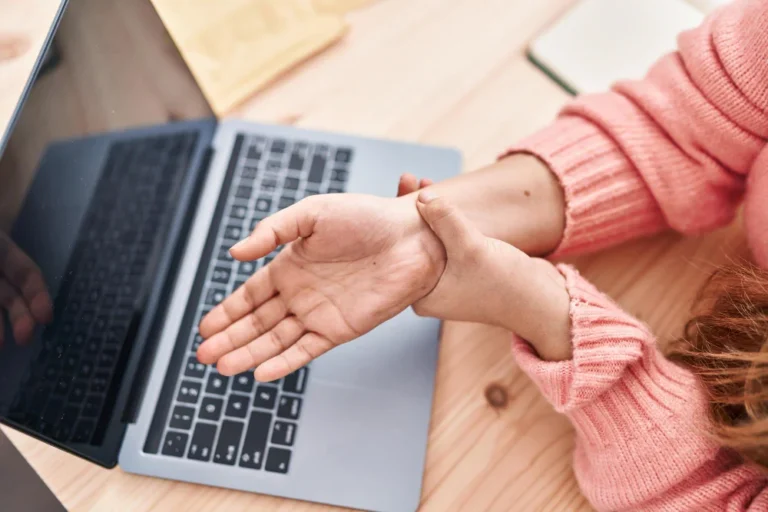Laptop user experiencing wrist pain from desk job