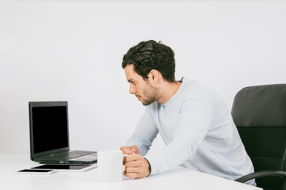 Person sitting with poor posture while using phone or laptop daily