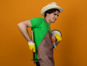 Person gardening and bending while experiencing lower back strain outdoors