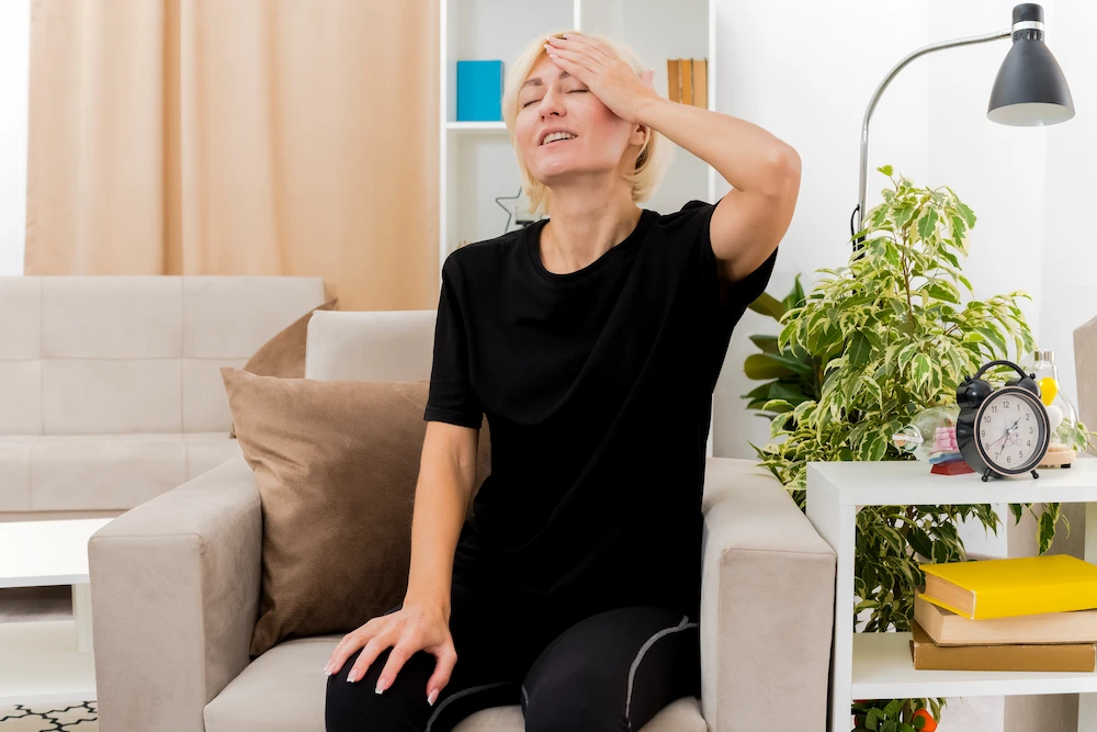 Person feeling tired and stressed while managing discomfort at home