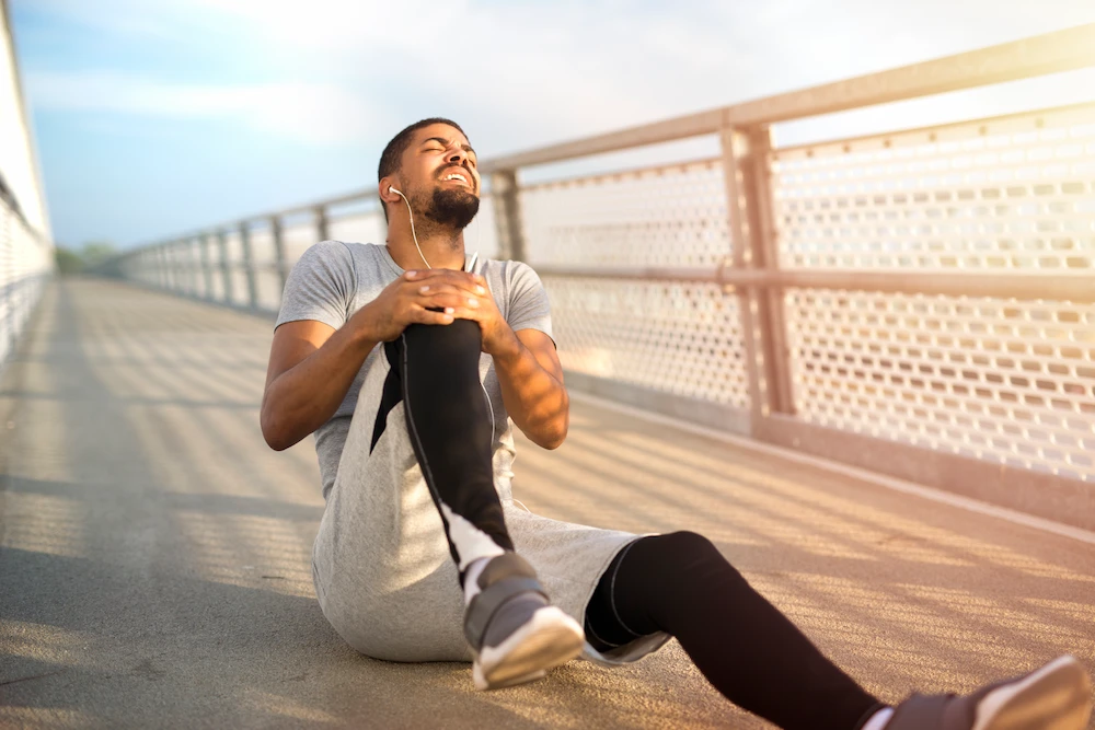 Person experiencing joint discomfort outdoors during hot summer weather