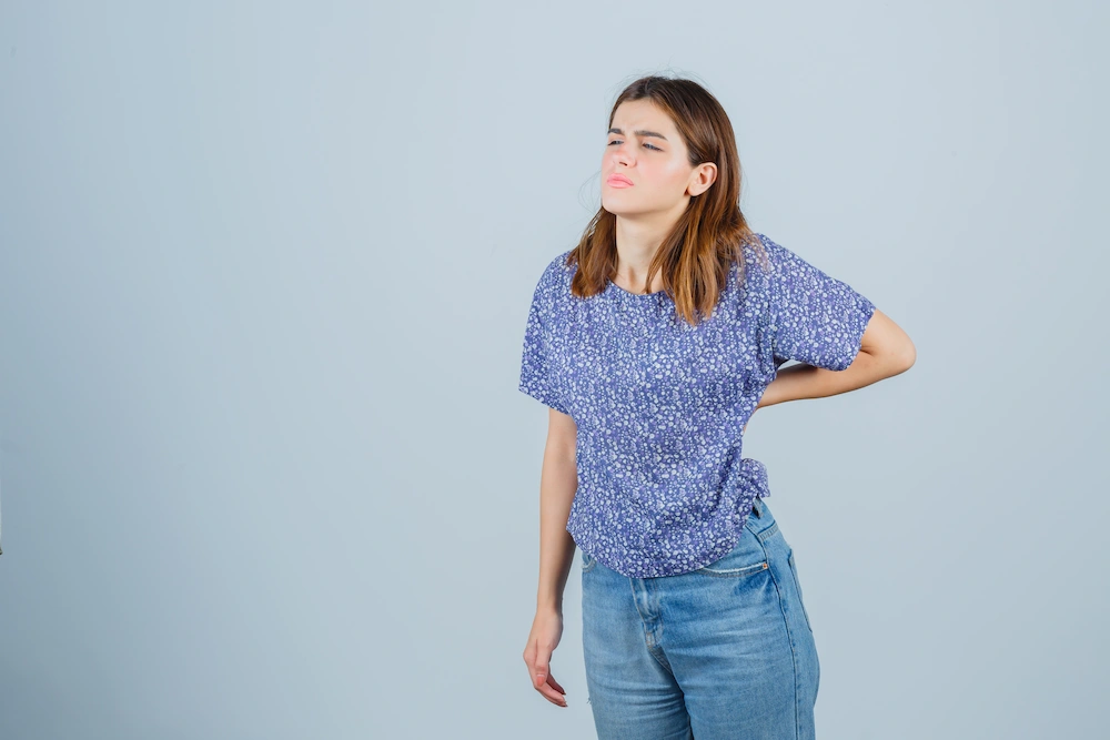 Young woman experiencing hip pain while standing