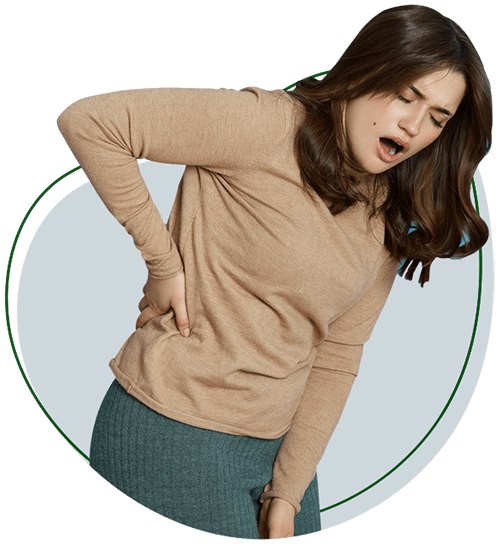 Gateway To Wellness Conditions Back Pain section image. Woman facing camera, leaning to the side with the opposite arm on her hip. Her eyes are closed, and her mouth is open, as if experiencing a sharp pain.