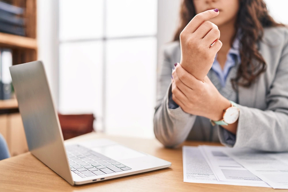 Woman experiencing hand pain from desk work posture