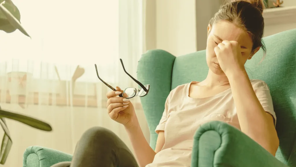 Woman holding her head due to migraine in a chair