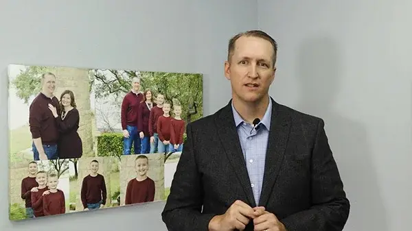 Embedded video image featuring Dr Jonathan Guymon standing in front of images containing his family and himself.