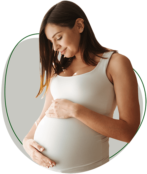 Pregnancy Chiropractic image. Pregnant woman looking down and smiling with hands on belly.