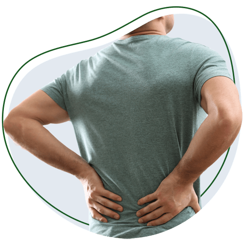 Person standing with hands on lower back, facing away from the camera, suggesting they have lower back pain.