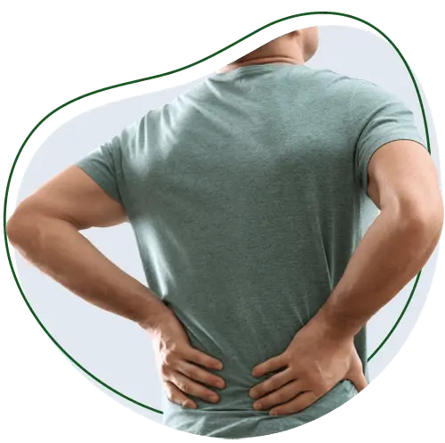 Person standing with hands on lower back, facing away from the camera, suggesting they have lower back pain.